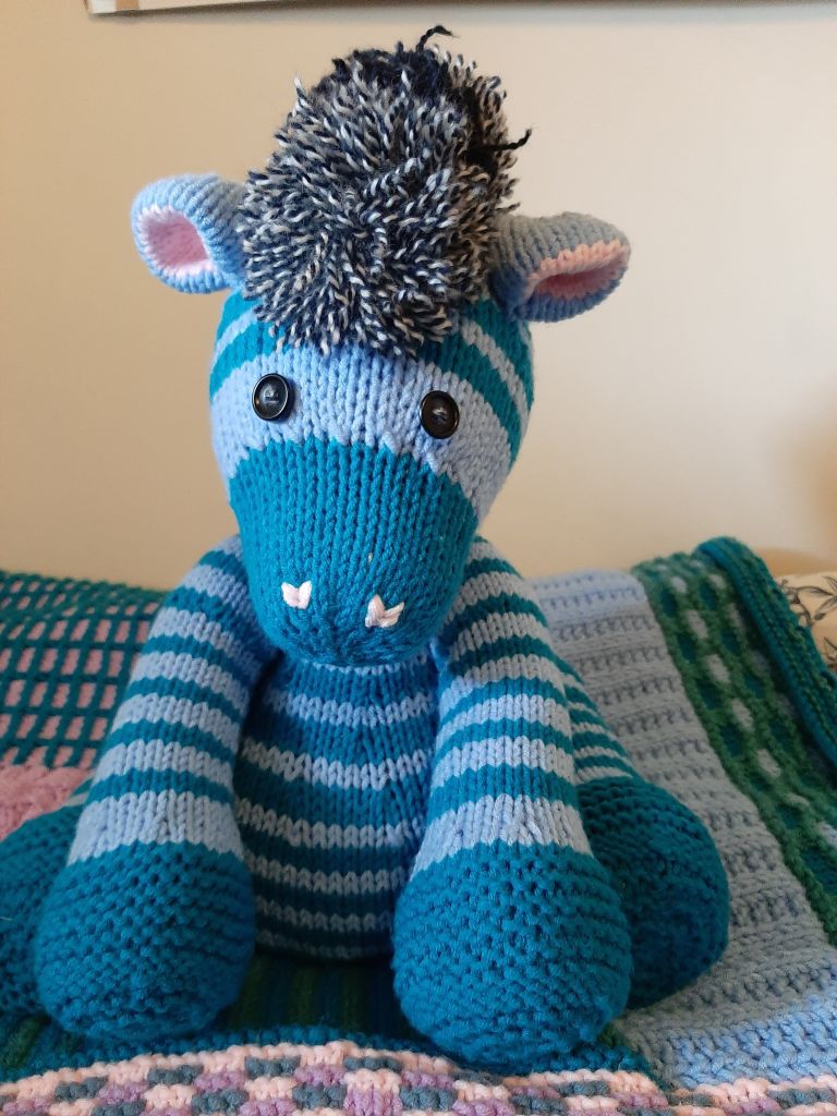 a zebra plushy with teal and light blue stripes